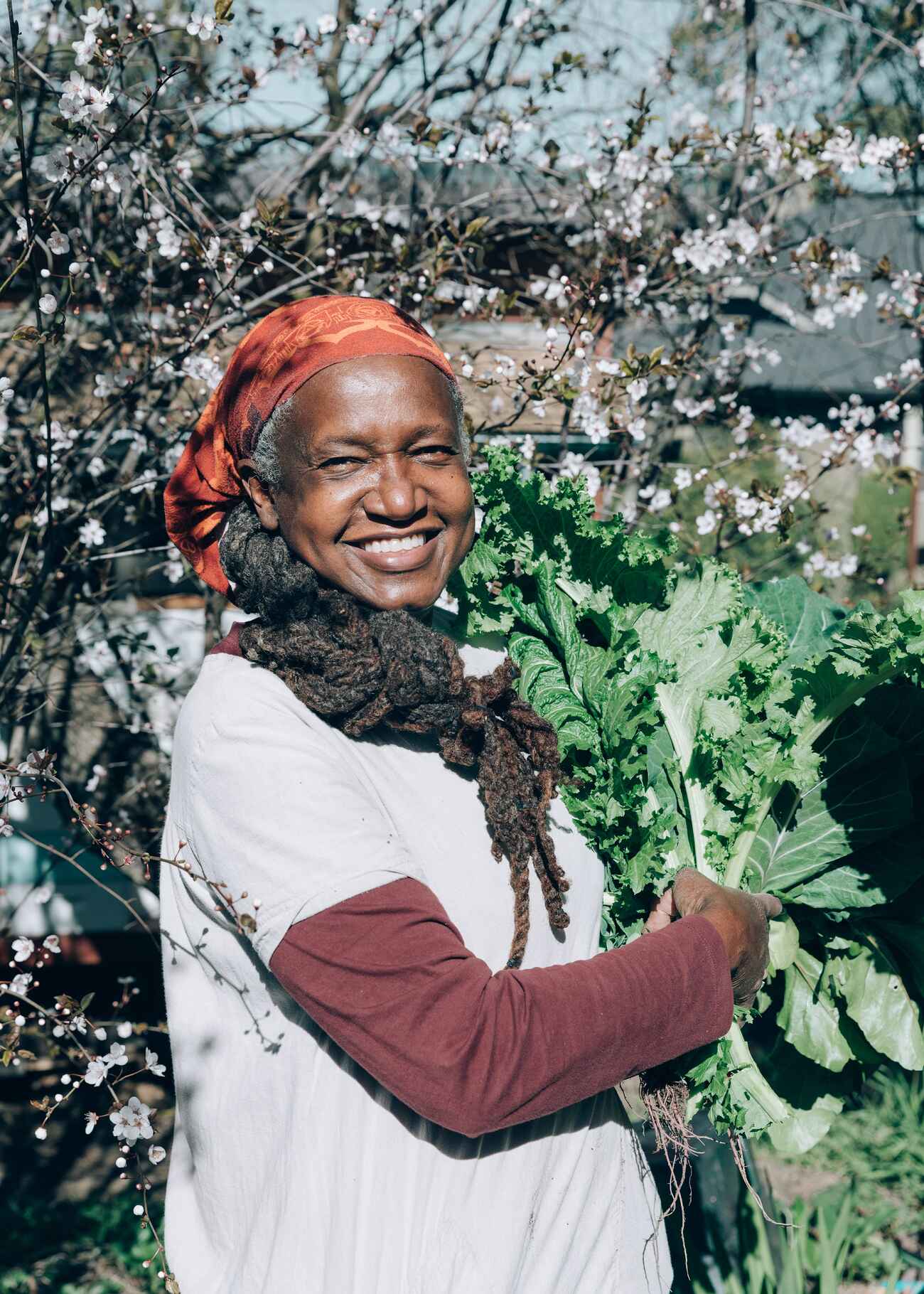 Woman in a garden holding leafy greens while standing among blooming flowers